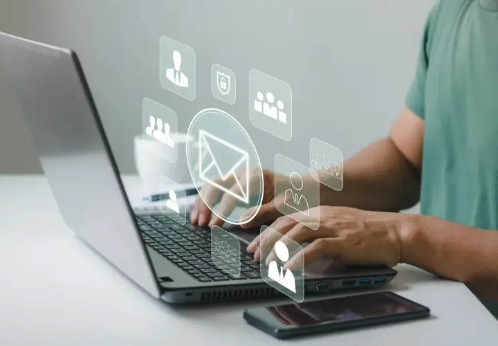 Man typing on laptop, with icons representing communication and security, suggesting a secure correo electrónico certificado.