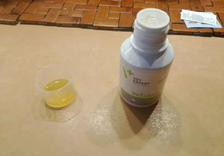 Płynna zawiesina **Vetussin** w kieliszku dozującym i butelce.