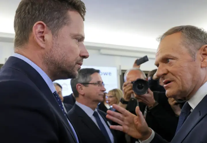 Czy Donald Tusk rzeczywiście obawia się ambicji prezydenckich Rafała Trzaskowskiego? Politycy rozmawiają w tłumie, w tle dziennikarze z aparatami.