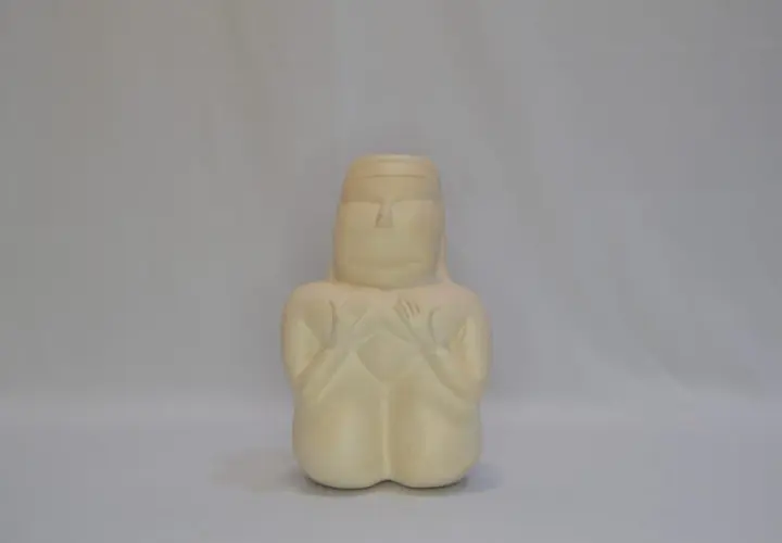 Figurina stilizzata che evoca la dea madre sarda, con mani giunte sul petto e un'espressione serena.