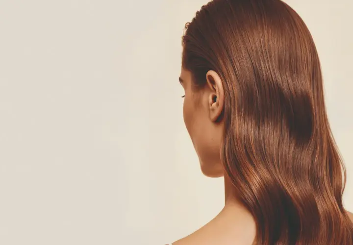 Cabello castaño brillante con un volumen envidiable, cayendo en ondas suaves sobre el hombro.