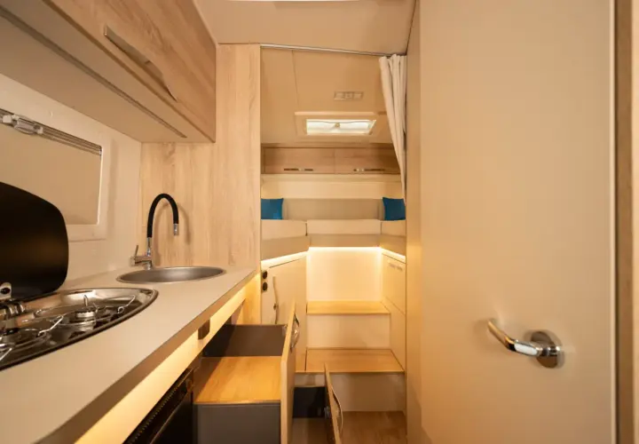 L'intérieur d'un camping-car moderne avec une cuisine fonctionnelle et un coin couchage confortable.