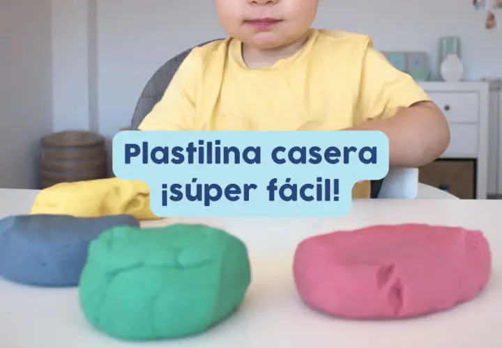Un niño sonriente listo para jugar con plastilina casera para niños de colores: azul, verde, amarillo y rosa.