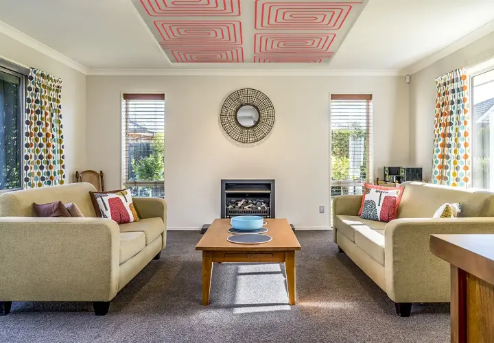 Salón acogedor con sofás, chimenea y un innovador techo radiante que calienta el ambiente.