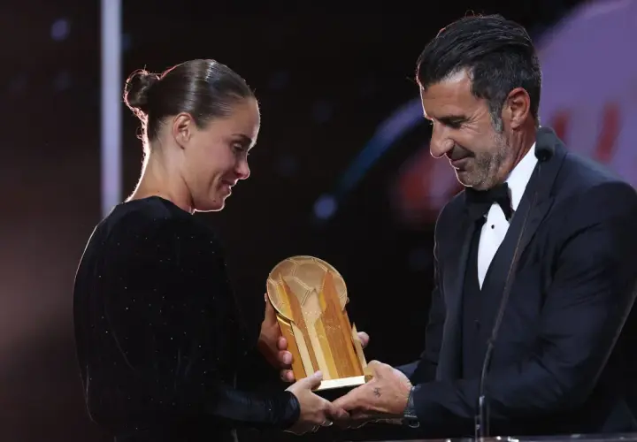 Piłkarz wręcza trofeum złota piłka kobiet.