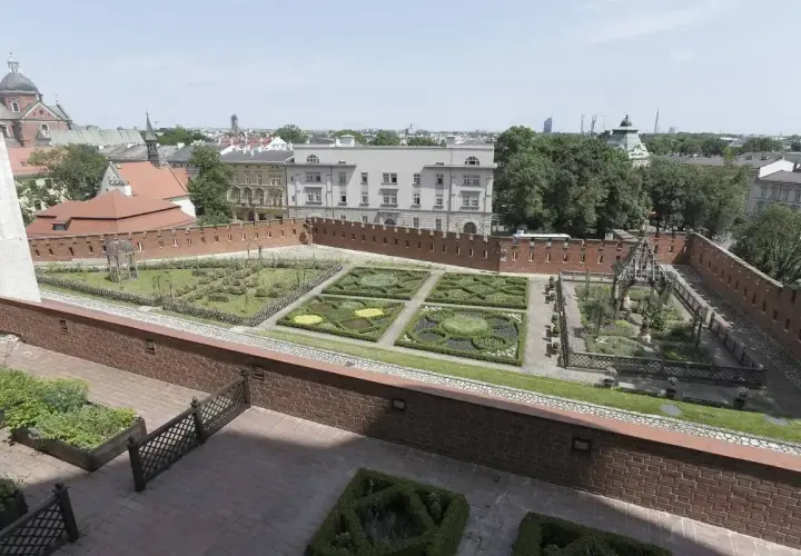 Krakowski ogród z geometrycznymi rabatami i architekturą, przypominający o dawnych czakramach w Polsce.