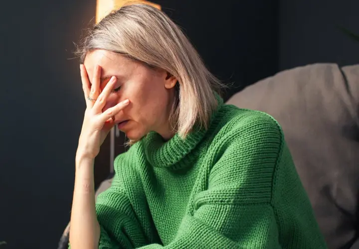 Donna con la mano sulla fronte, visibilmente provata. Un'immagine che evoca la lotta contro ansia e depressione, e la ricerca di come uscirne.