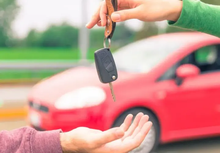 Passaggio di chiavi per vendere l'auto velocemente. Una mano porge le chiavi di un'auto rossa a un'altra mano.