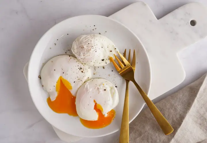 Trois œufs pochés parfaits, avec leurs jaunes coulants, assaisonnés de poivre noir. Un délice de différents types d'œufs pour un petit-déjeuner gourmand.