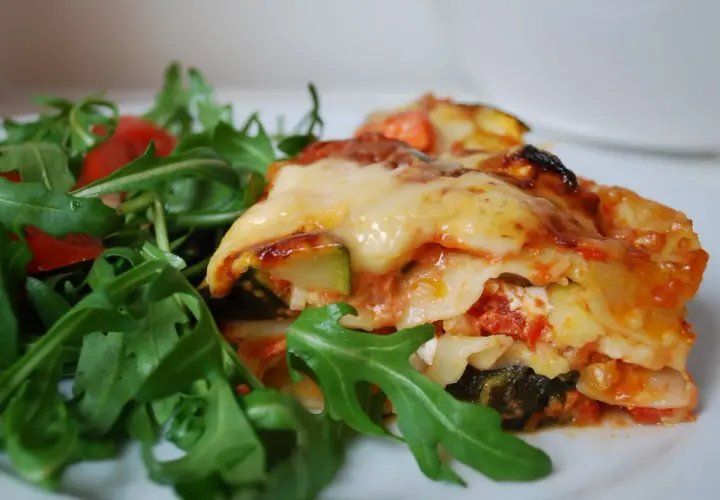 En bit krämig grönsakslasagne med ruccolasallad, perfekt för en vegetarisk recept topplista.