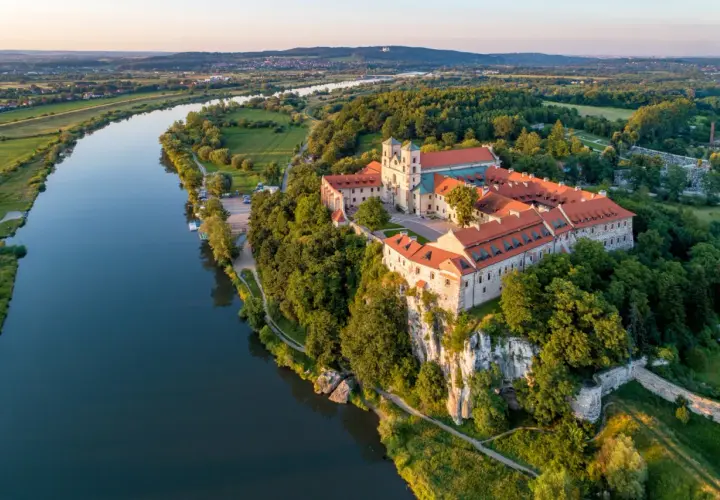 Opactwo Benedyktynów w **Tieńcu** majestatycznie wznosi się nad Wisłą, otoczone zielenią.