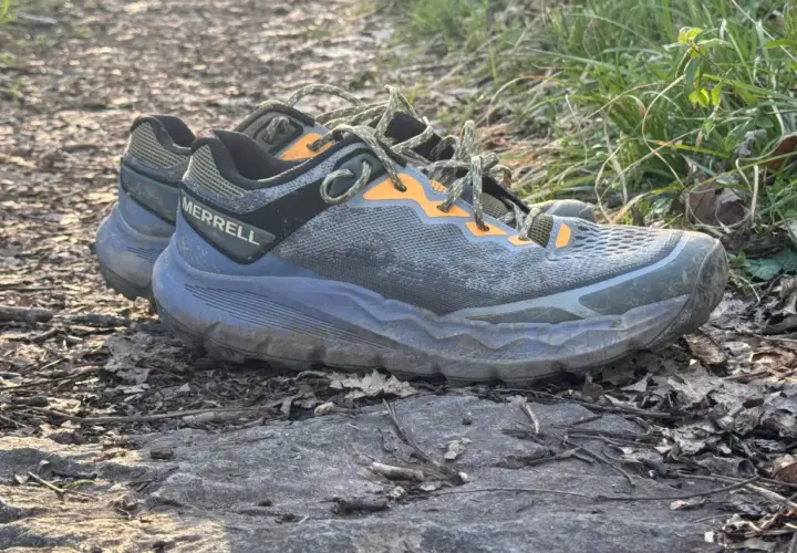 A pair of Merrell Nova 4 trail running shoes rests on a rocky path, ready for adventure.
