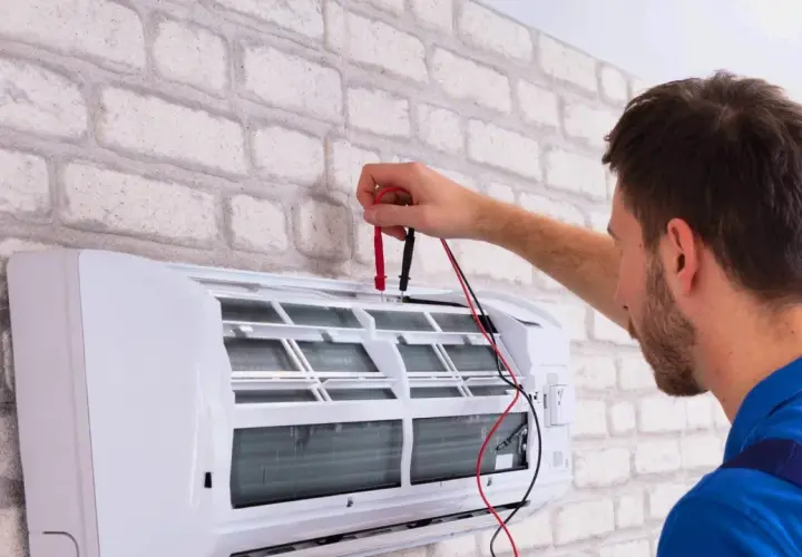 Technik sprawdza klimatyzator, który nie chłodzi. Używa multimetru do diagnozy problemu.