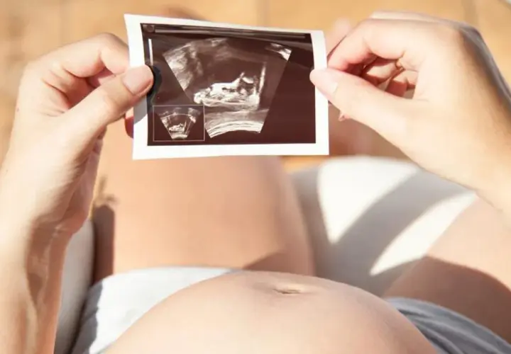 Kobieta trzyma zdjęcie USG płodu. Choć nie ma tu mowy o lewatywie ani jej skutkach ubocznych, obrazek symbolizuje początek nowego życia.