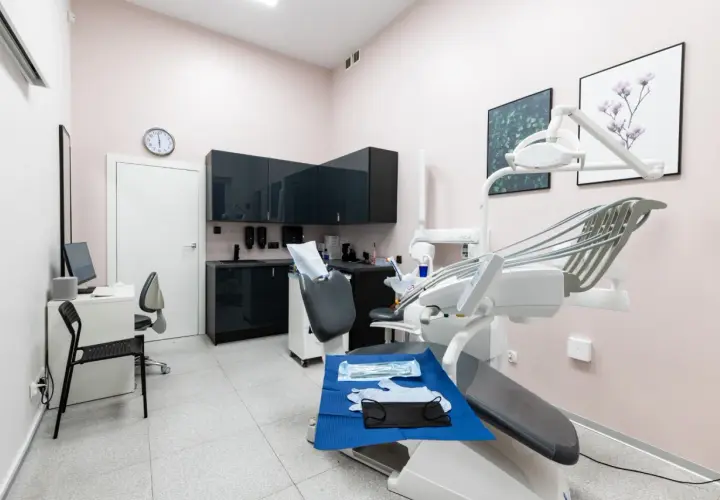 Nowoczesny gabinet stomatologiczny z fotelem dentystycznym i wyposażeniem.