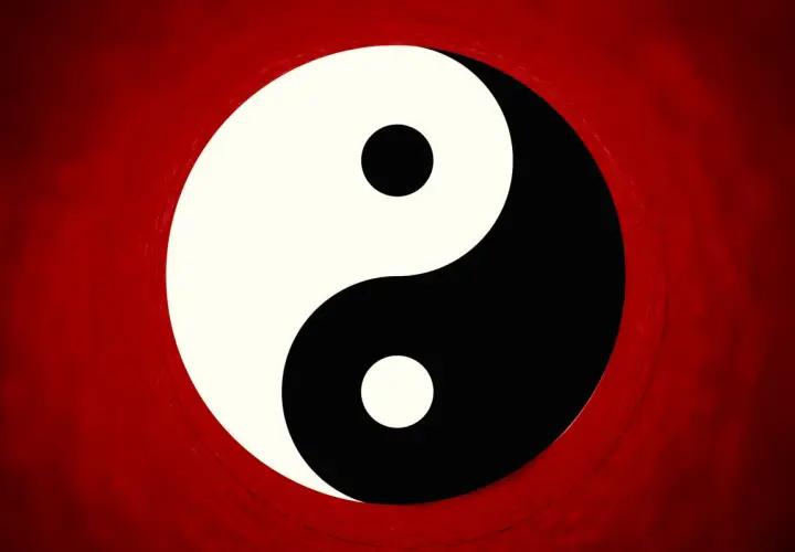 Il simbolo Yin e Yang, principio della filosofia orientale, su sfondo rosso sfumato.