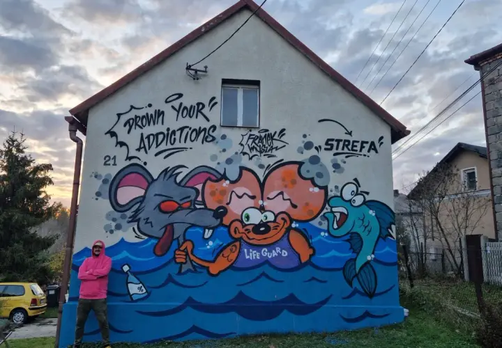 Kolorowy mural na domu jednorodzinnym przedstawia kreskówkowe zwierzęta w wodzie. Widać mysz, małpkę z napisem "LIFE GUARD" i rybę.