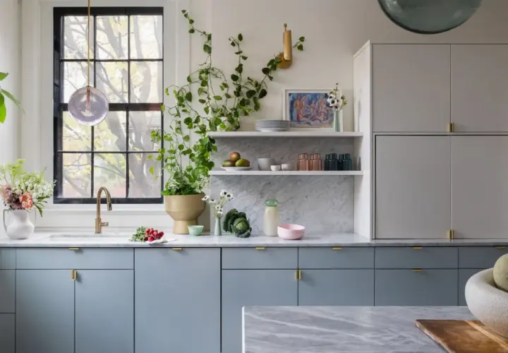 A modern kitchen with popular kitchen cabinet colors: soft blue lower cabinets and light gray upper cabinets, accented with brass hardware.