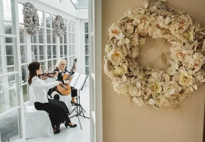 Dwie artystki tworzą oprawę muzyczną ślubu w kościele: jedna gra na skrzypcach, druga na gitarze.