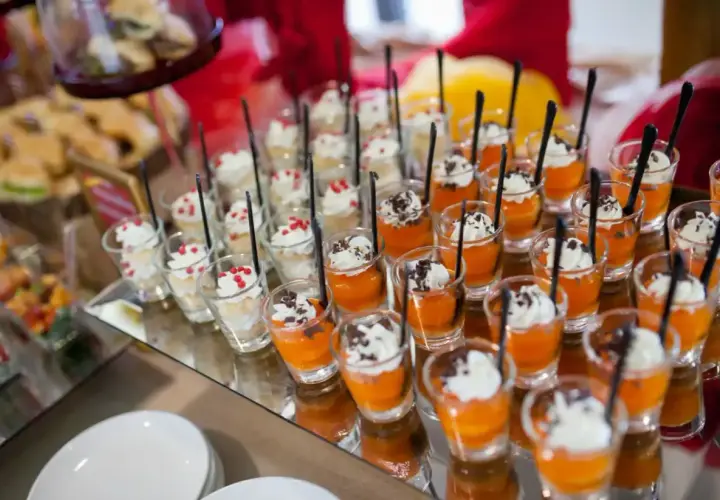 Petits desserts individuels en verrines, certains à la crème et fruits rouges, d'autres à la mousse orange et copeaux de chocolat. Un nom de menu original serait parfait pour ces délices.