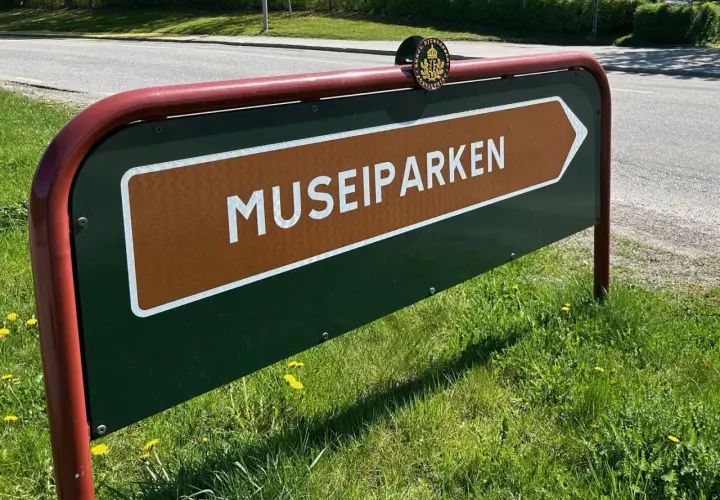 Skylt som pekar mot Museiparken Stockholm. En grön skylt med en brun pil och texten "MUSEIPARKEN" i vitt.