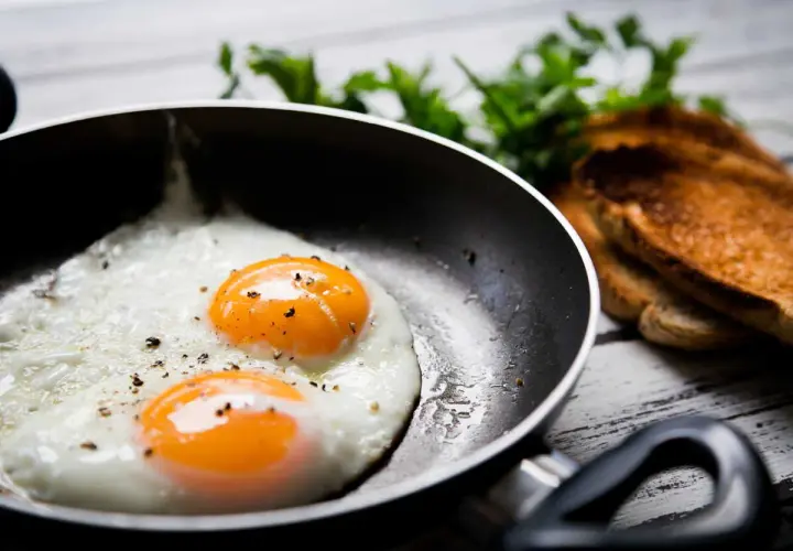 Deux œufs au plat parfaits dans une poêle, prêts à être dégustés. Une idée simple pour comment faire des oeufs au plat.