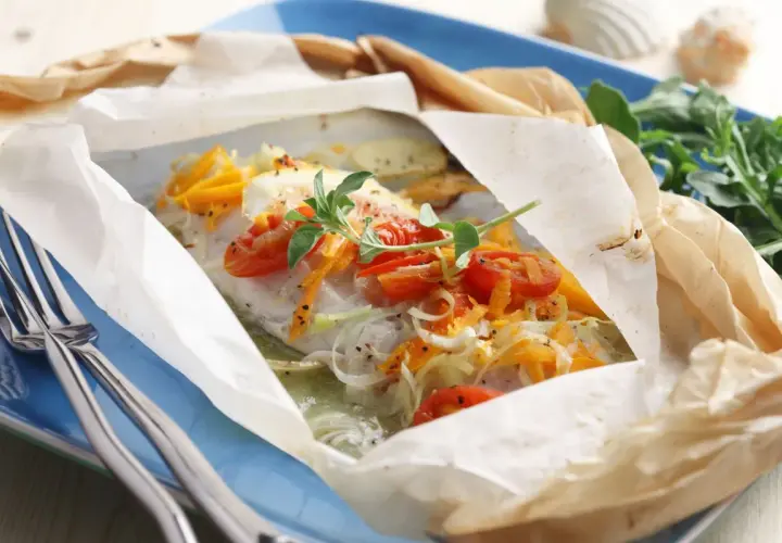 Un plat de cabillaud en papillote, garni de tomates cerises et d'herbes. Un délice pour savoir quel vin avec du cabillaud.