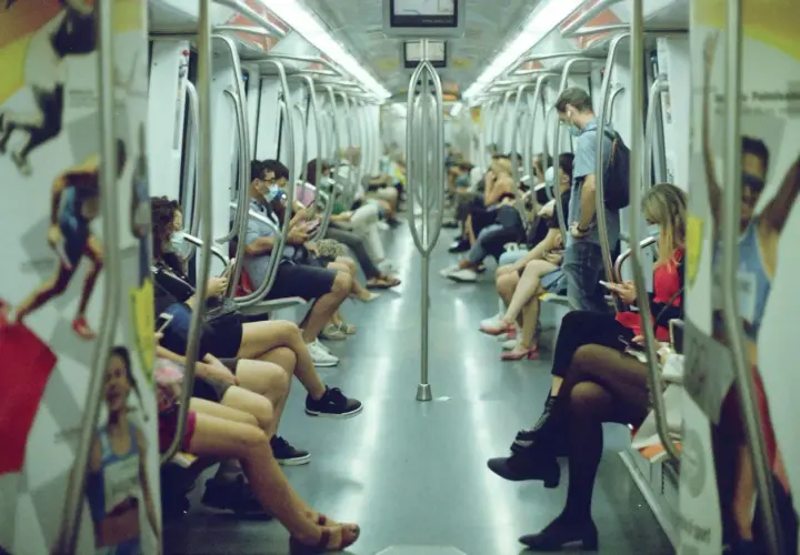 Interno di un vagone della metro di Roma, con passeggeri seduti e in piedi. L'orario del metro è visibile su un cartello.