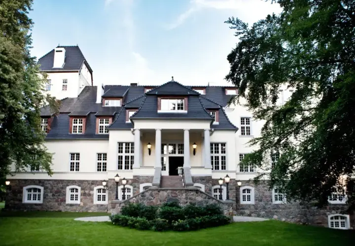 Elegancki pałac w Ciekocinku otoczony zielenią, z kamienną podstawą i kolumnowym wejściem.