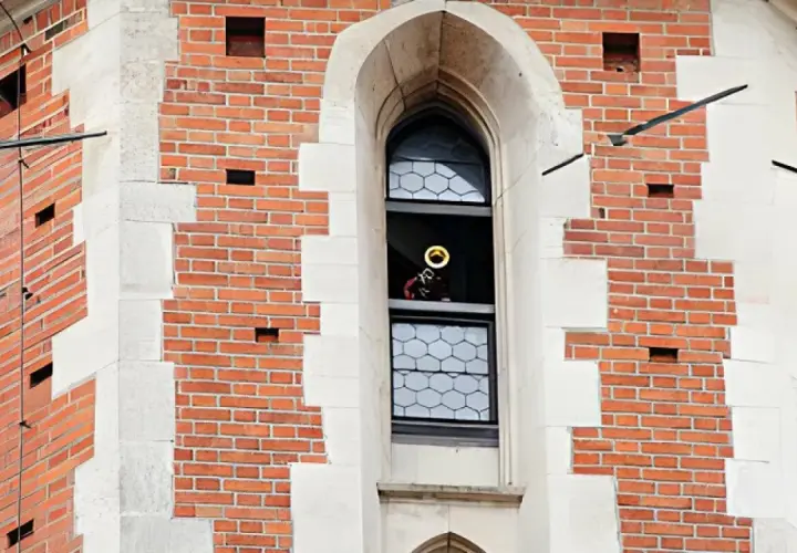 Trębacz gra hejnał mariacki z okna wieży.