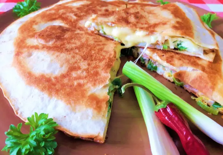 Złocista tortilla z jajkiem, serem i szynką, usmażona na patelni, z dodatkiem szczypiorku i papryczki.