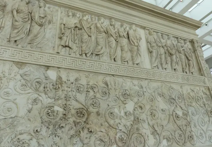 Bas-reliefs de l'Ara Pacis à Rome, représentant des figures toges et des motifs floraux complexes.