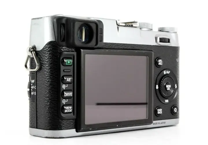 Tył aparatu Fujifilm X100S z widocznym ekranem, przyciskami sterującymi i pokrętłami.