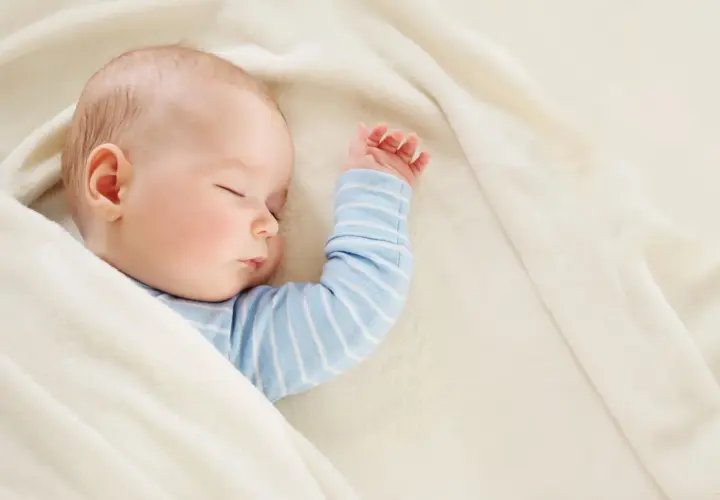 Śpiące dziecko, 22 tydzień życia, otulone w miękki kocyk.