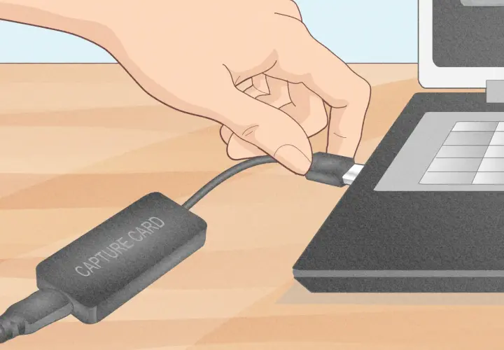 Dłoń podłącza kabel karty przechwytującej do laptopa.