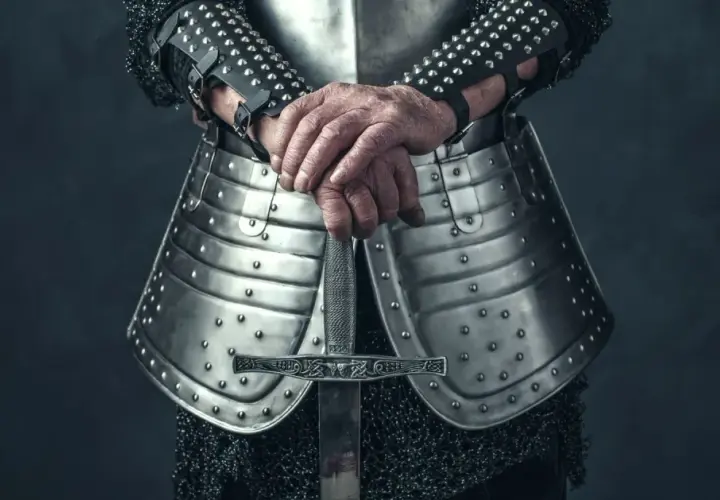Rycerz w zbroi trzyma miecz. Może szukać bannerlord cheats, by zdobyć przewagę w bitwie.