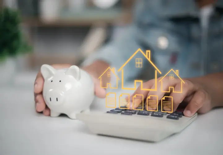 Une tirelire et une calculatrice avec des icônes de maisons et de documents. Une autre solution que le prêt relais pour financer votre projet immobilier.