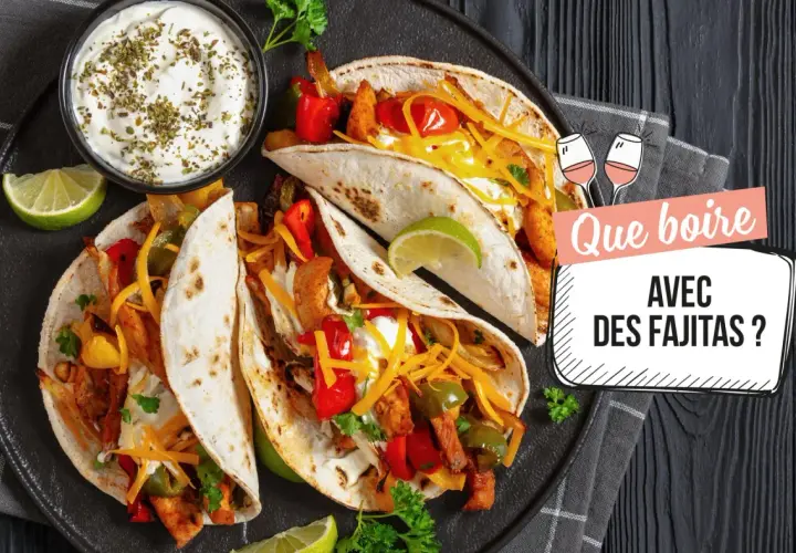 Assiette de fajitas savoureuses avec garnitures, crème aigre et quartiers de citron vert. Le texte demande "Que boire avec des fajitas ?".