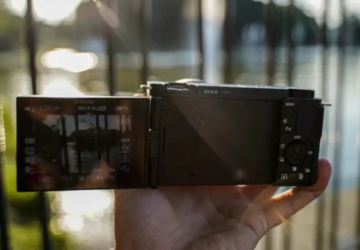 Dłoń trzyma aparat Sony Alpha ZV-E10 z uchylonym ekranem, na którym widać ustawienia nagrywania 4K.