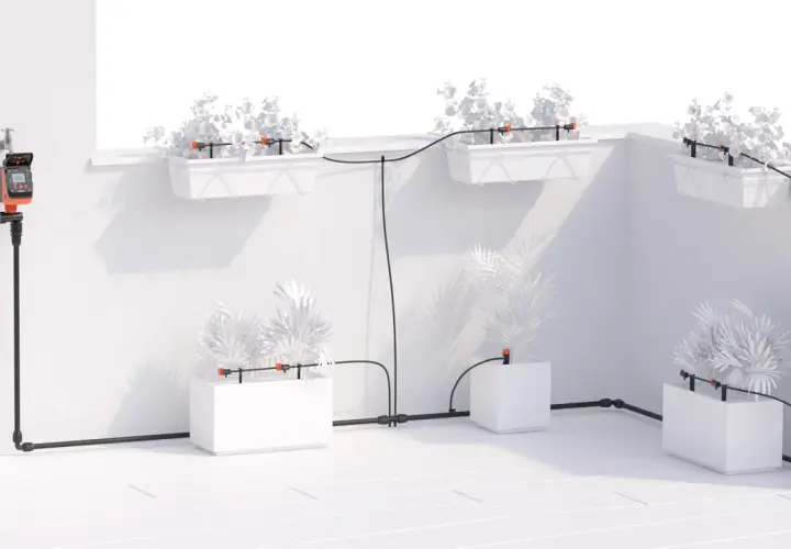 Sistema di irrigatore automatico per vasi fai da te con timer digitale collegato al rubinetto, che distribuisce acqua a piante in fioriere e vasi.