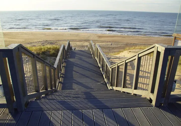Schody prowadzące na plażę w Darłówku. Promenada z widokiem na morze i piasek.