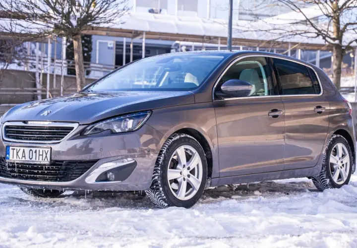 Szary Peugeot 308 na zimowych oponach, gotowy na śnieżne drogi. Wiele pozytywnych peugeot 308 opinie potwierdza jego wszechstronność.