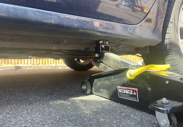 Lewarek podłożony pod wzmocnienie progu samochodu. Widać podnośnik i miejsce, gdzie podłożyć lewarek, by bezpiecznie podnieść auto.