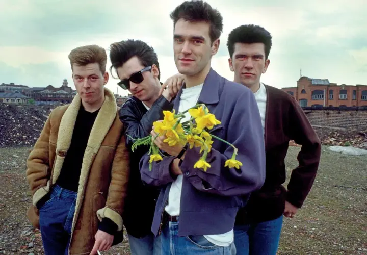 Członkowie The Smiths pozują z bukietem żółtych żonkili na tle postindustrialnego krajobrazu.