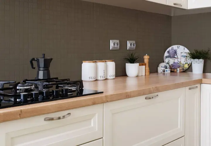 Fornelli neri su piano in legno, con barattoli per zucchero, tè e caffè. Sfondo con piastrelle effetto vernice per piastrelle cucina.