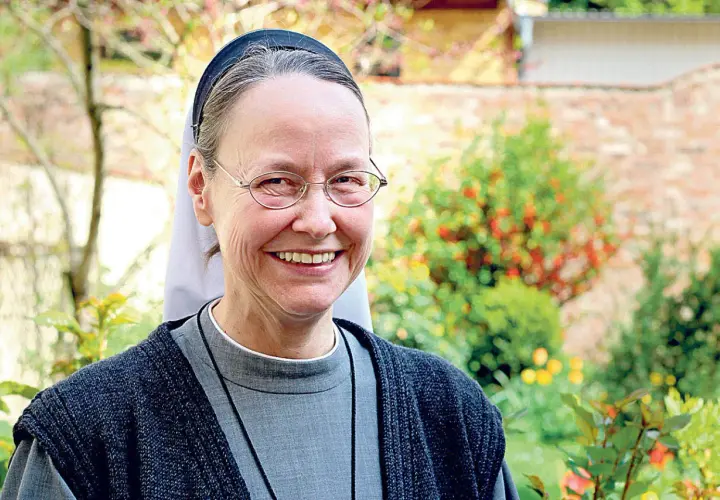 Lächelnde evangelische Nonne mit Brille im Garten.