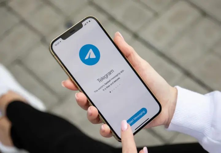 Dłoń trzyma smartfon z otwartą aplikacją Telegram, która reklamuje się jako szybka i bezpieczna. Czy telegram jest bezpieczny?