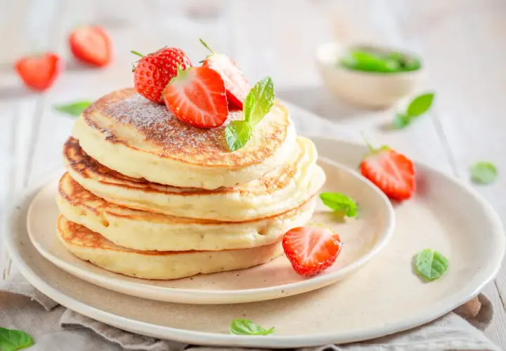 Pile de pancakes moelleux, décorés de fraises fraîches et de menthe, comme ceux de Cyril Lignac. Un délice !