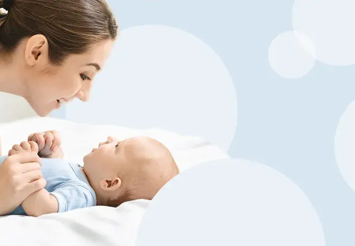 Mama patrzy z miłością na swoje dziecko, które właśnie zaczyna gaworzyć, wydając pierwsze dźwięki radości.