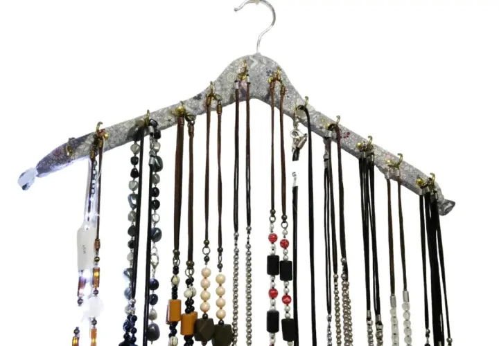 Percha para collares con multitud de cadenas y colgantes de diversos materiales y colores, organizados de forma ordenada.
